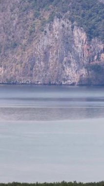 Phang Nga Körfezi 'nin kireçtaşı kayalıklarının sakin manzarası ve yumuşak gün ışığında sakin sular, pürüzsüz bir dönüş hareketiyle yakalanır.