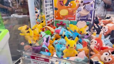 Renkli peluş oyuncaklarla dolu bir pençe makinesi.