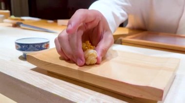 Şef ahşap servis tahtasına suşi koyar.