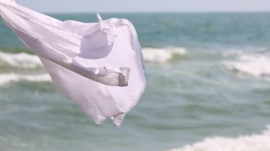 Beyaz bez dalgaları okyanus dalgalarına karşı dalgalanır.