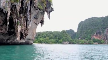 Uzun kuyruklu tekne çarpıcı Krabi kaya oluşumlarını geçiyor