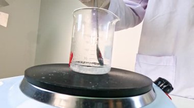 Bir bilim adamı, kimyasal reaksiyonlar gösteren bir laboratuvar ortamında sodyum asetatla kristalizasyon deneyi yürütüyor.