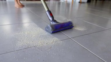 Elektrikli süpürge fayanslı mutfak zeminindeki kırıntıları etkili bir şekilde temizler, temizlik ve modern ev bakımını ön plana çıkarır.