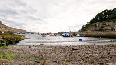 Dalgalar kıyıya vururken arka planda tekneler