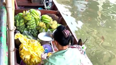 Satıcı Bangkok 'ta bir teknede meyve satıyor.