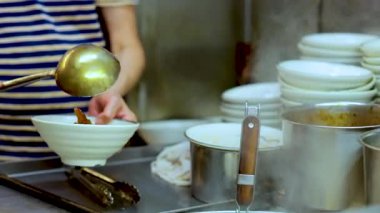 Şef, meşgul bir mutfakta ustalıkla erişte hazırlar.