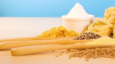 Tahıl, makarna ve ekmek çeşitleri parlak ışık altında mavi bir arka plan ile ahşap bir yüzey üzerinde düzenlenmiş