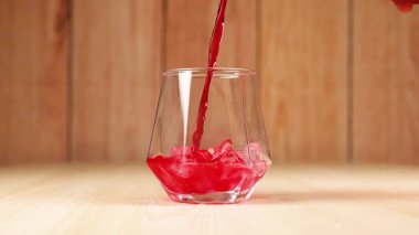 Kırmızı içki buzlu bardağa döküldü.