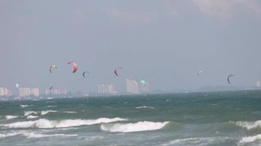 Uçurtma sörfçüleri şehrin ufuk çizgisine yakın dalgaların üzerinde süzülür.