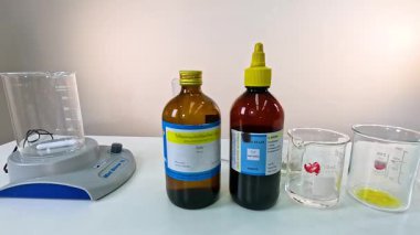 Kimyasal çözümler ve laboratuvar ekipmanları beyaz bir masada parlak ışık altında iyot saat reaksiyon deneyi için düzenlendi.