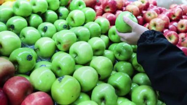 Dükkanda yeşil elmaya uzanan