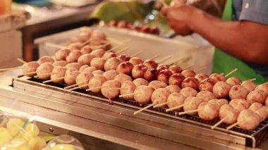 Satıcı, yüzen markette ızgara sosis yapıyor.