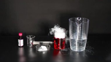 Kuru buz kırmızı sıvıyla tepkimeye girer ve buhar yaratır.