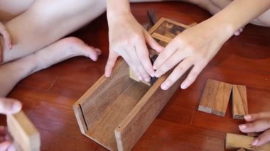 Birlikte ahşap bir bulmacayı çözerken birden fazla el.