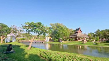 Bangkok 'taki Rama IX Parkı' nda yemyeşil ve sakin sularla dolu berrak gökyüzünün altında sakin bir pavyon.