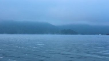 Uzak dağlarla sisli nehir manzarası