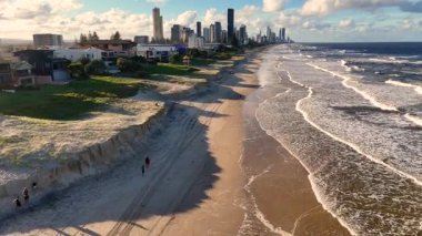 Havadan çekilen görüntüler, Avustralya 'nın Gold Coast bölgesinde kumlu sahilleri, okyanus dalgalarını ve açık gökyüzü altında yakınlardaki şehir manzarasını gösteren aşınmayı yakalıyor.