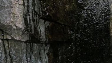 Suyun yakın plan bir kaya yüzeyinden aşağı akışı