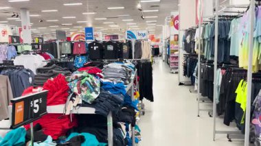 Giysiler kalabalık bir mağazada sergileniyor.