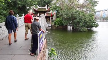 İnsanlar göl köprüsünün üzerinden tapınağa doğru yürüyorlar