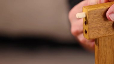 Eller, yumuşak ışıklandırma altında ahşap mobilya eklemlerine pervazlar takar. Bu da ustalık ve montaj tekniklerini gösterir.