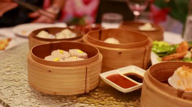 Dim sum, bambu sepetleri ve soslarla dolu canlı bir masa, canlı bir yemek deneyimi yakalıyor.