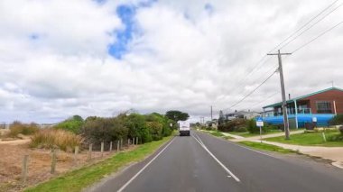 Büyük Okyanus Yolu boyunca sakin bir yolculuk yemyeşil, berrak gökyüzü ve gün ışığında çekilen kıyı manzarası.
