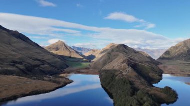 İnsansız hava aracı görüntüleri Moke Gölü 'nün sakin manzarasını ve Queenstown, Yeni Zelanda' daki açık mavi gökyüzünün altında çevreleyen dağları yakalar.