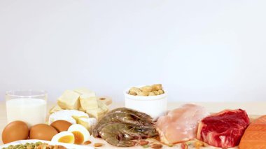 Fındık, yumurta, süt ürünleri ve etler de dahil olmak üzere çeşitli protein zengini yiyecekler bir masada güzelce düzenlenir.