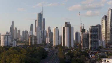 İnsansız hava aracı görüntüleri, sıcak bir günbatımı parıltısı altında yüksek binalar ve inşaat vinçleriyle Gold Coast ufuk çizgisini yakalıyor.