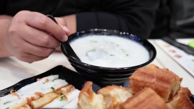 Kızarmış hamur çubuklarıyla pirinç lapası yiyen biri.