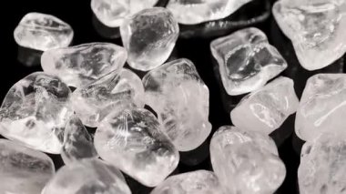 Açık kuvars taşları parlak ışıklandırmayla siyah bir yüzey üzerinde gösterilir, şeffaflık ve dokularını vurgular.