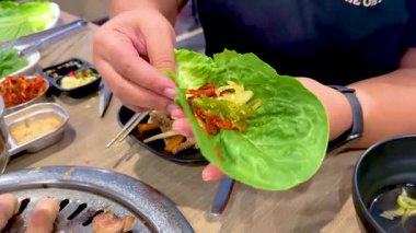 El, Kore barbekü paketini kıvrak bir Bangkok ortamında marul ve ızgara etle birleştiriyor. Parlak ışıklandırma aşçılık sürecini güçlendirir