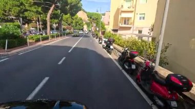 Park etmiş scooterlarla huzurlu bir sokak manzarası.