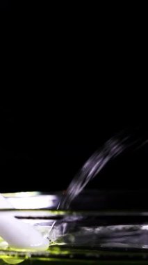 Bir beyaz çubuk sıvıyla etkileşime girer ve yansıtıcı yüzeylerle karanlık bir ortamda sabun köpükleri oluşturur.