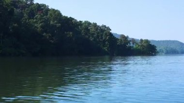 Sakin bir göl boyunca ilerleyen bir tekne..