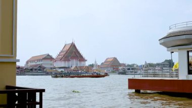 Bangkok Tayland 'daki geleneksel binaların yakınlarındaki nehir boyunca seyahat eden tekne.