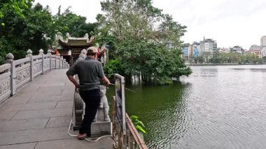 İnsanlar bir köprüde balık tutup yürüyor.