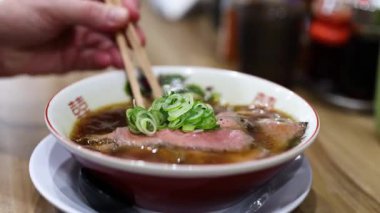 Restoranda çubukla ramen yiyen biri.