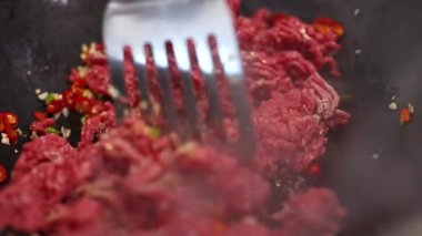 Yakın plan sığır eti kızartması canlı malzemeler ve buharla dolu bir tavada pişiyor.