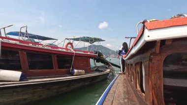 Açık bir günde rıhtımdaki teknelerin arasına giren kişi