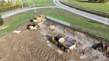 İnsansız hava aracı Cromwell, Yeni Zelanda 'da güneşli bir günde kazıcıyı ve çöp kamyonunu iş yerinde yakalıyor.