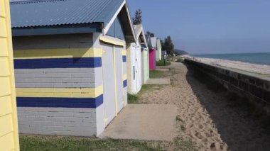 Kumlu bir patika boyunca renkli plaj kutuları