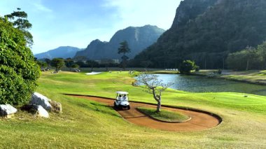Golf arabası pitoresk bir golf sahasında yol alıyor.