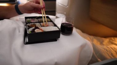 Suşi yiyen ve uçakta şarap içen biri.