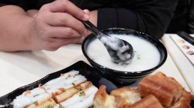 Hong Kong 'da hamur çubuklarıyla pirinç lapası yiyen biri.