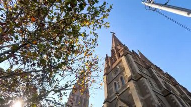 Etrafı ağaçlarla çevrili güneşli kilise cephesi