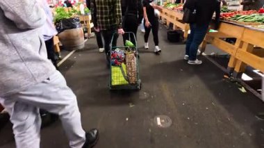 İnsanlar kalabalık bir pazarda alışveriş yapıyorlar.