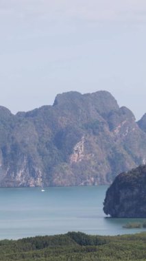 Phang Nga Körfezi 'nin sakin panoramik manzarası yemyeşil, kireçtaşı kayalıkları ve berrak gökyüzünün altındaki sakin sular.