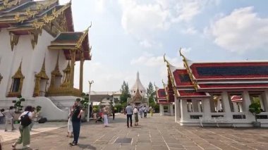 Turistler Bangkok 'taki süslü Wat Phra Kaew tapınağını keşfederek, aydınlık gün ışığında karmaşık mimarisini yakalıyorlar.